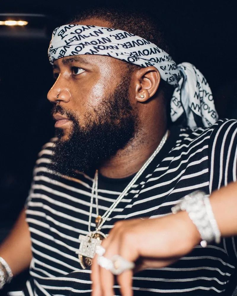 Cassper Nyovest de profil, bandana NYOVEST, t-shirt rayé et chaînes