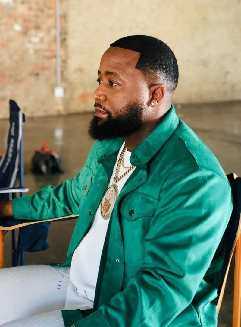 Cassper Nyovest de profil en veste verte satinée, gros pendentif doré, en interview