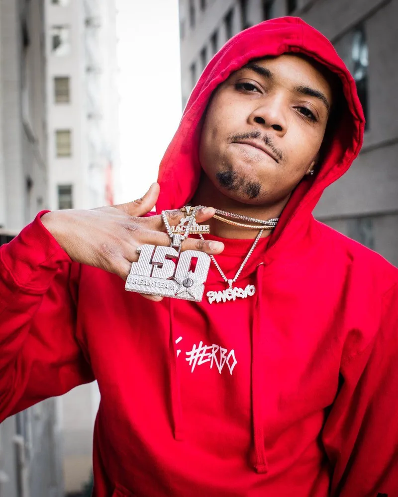 Le rappeur G Herbo en hoodie rouge, pendentif 150, dans une rue