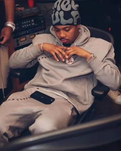 G Herbo en studio, survêtement gris, assis près d'une console