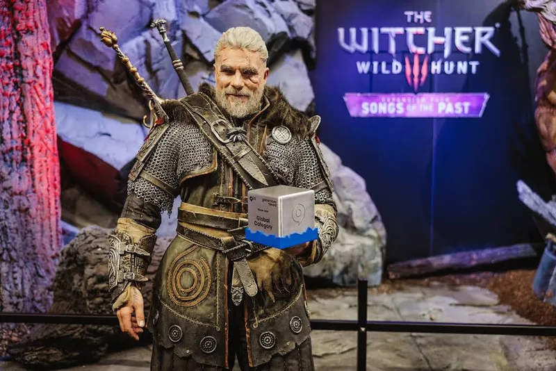 Cosplay de Geralt (The Witcher 3) tenant un trophée sur le stand CD Projekt Red à la Gamescom