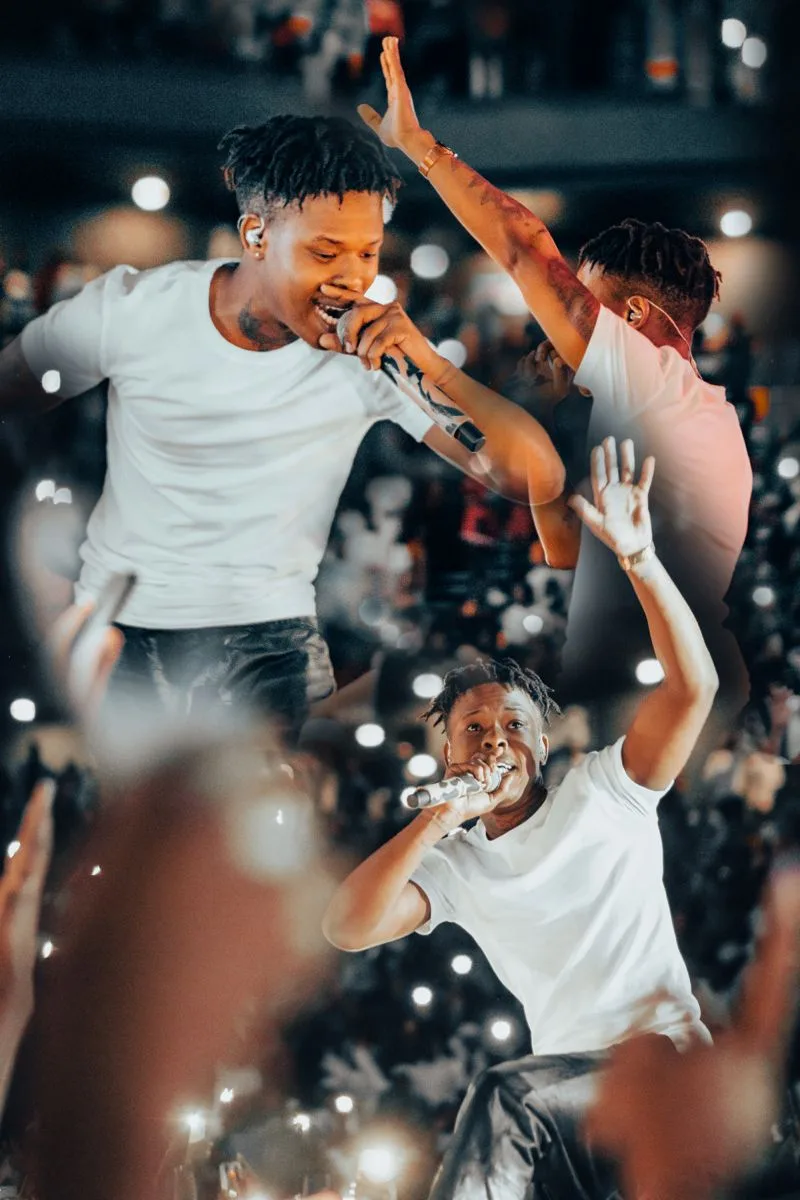 Nasty C sur scène en concert, micro en main, un second artiste à ses côtés, foule illuminée par les téléphones