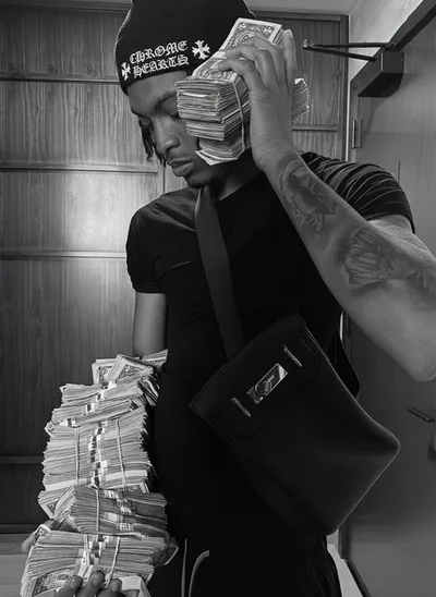 Nemzzz en noir et blanc, bonnet Chrome Hearts, tenant des liasses de billets