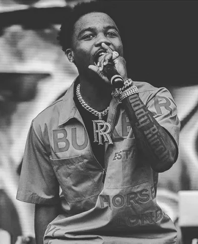 Roddy Ricch en noir et blanc, chemise Burberry, micro en main sur scène
