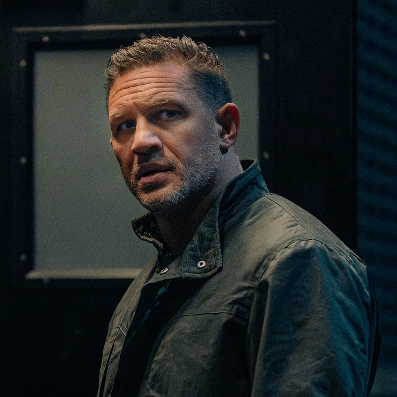 Portrait de l'acteur Tom Hardy, veste verte, regard par-dessus l'épaule