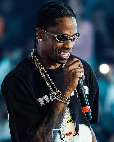 Travis Scott en concert, micro en main, lunettes et chaînes en or