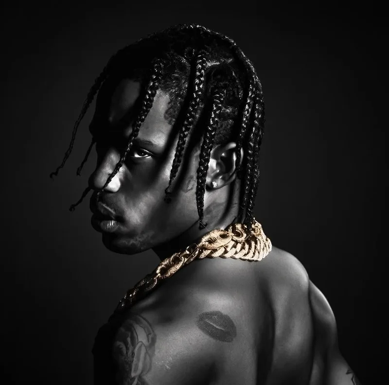 Travis Scott de profil en noir et blanc, tresses et grosse chaîne en or